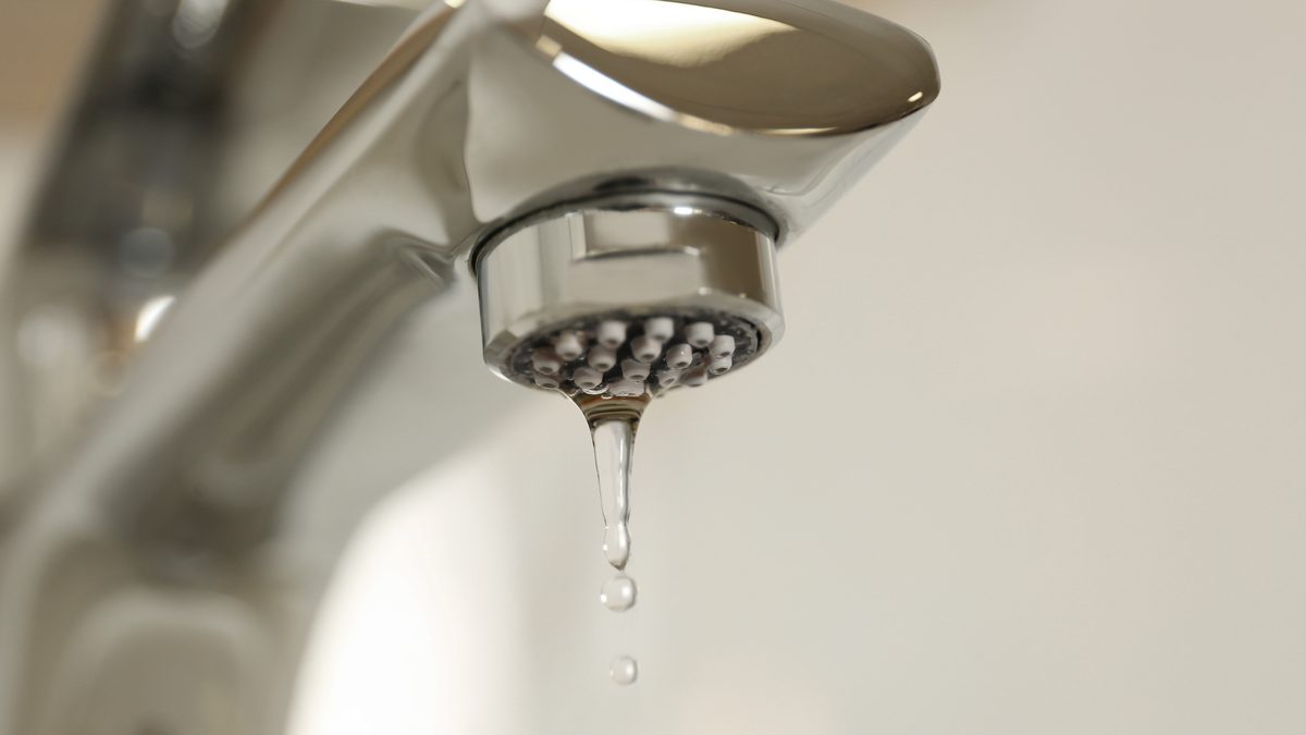 Water drops falling from a fitting against a dark background