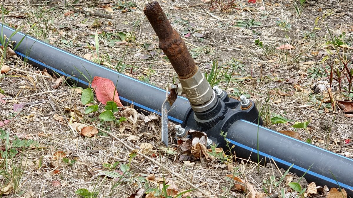 Rusted riser on a tapping saddle clamped to a buried supply main